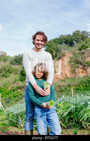 Father and son holding lettuce seedlings in a vegetable garden Stock Photo