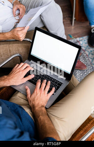 Close-up of businessmen with laptop and documents sitting in armchairs Stock Photo