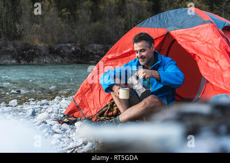 Mature man camping at riverside, espresso maker and cup Stock Photo
