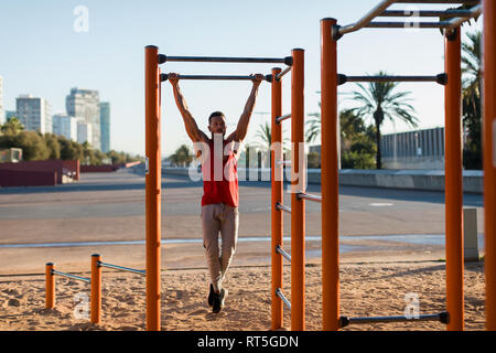 Fit man working out in climbing parcour, doing pull ups Stock Photo