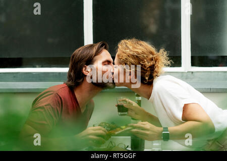 Happy couple kissing at the table, eating pizza, drinking wine Stock Photo