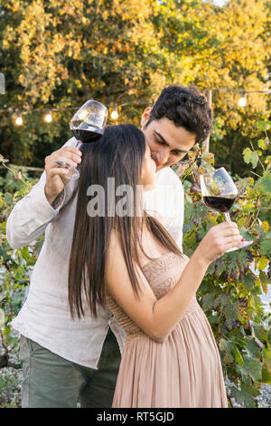 Italy, Tuscany, Siena, affectionate young couple with red wine glasses in a vineyard Stock Photo