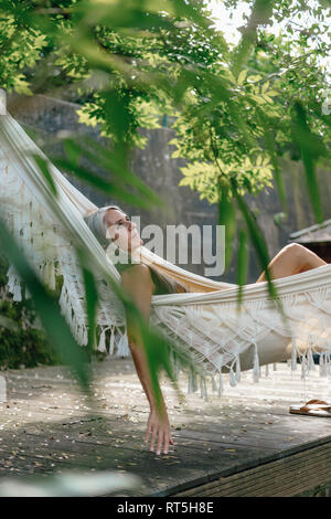 Pensive woman relaxing in hammock in the garden Stock Photo