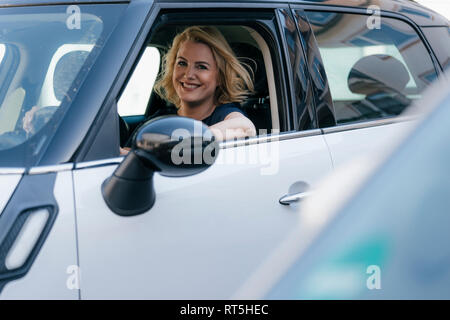 Portrait of smiling woman looking out of car window Stock Photo