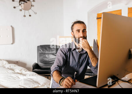 Smiling young man working at home using the computer Stock Photo