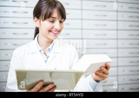 Smiling pharmacist with tablet and tablet package in pharmacy Stock Photo