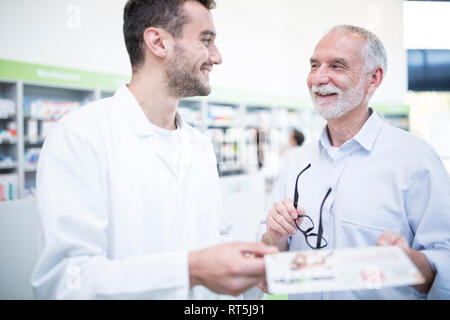 Pharmacist smiling at mature man in pharmacy Stock Photo