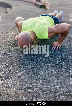 Muscular man doing push-ups outdoors Stock Photo