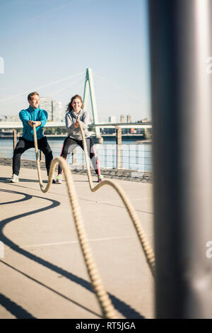 Friends training at the riverside, pulling rope Stock Photo