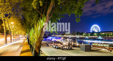 France, Paris, Champs-Elysees, Quai Anatole, people at River Seine bank at night Stock Photo