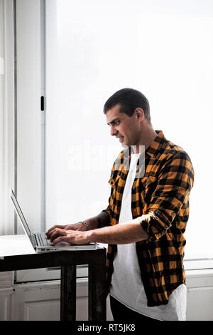 Smiling young man using laptop at table Stock Photo