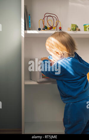 Baby girl taking toys from shelf Stock Photo
