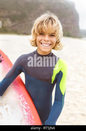 Spain, Aviles, portrait of smiling young surfer on the beach Stock Photo