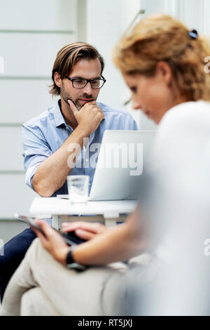 Happy couple working from home, sitting in their garden Stock Photo