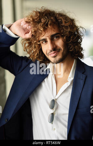 Portrait of stylish young man with beard and curly hair smiling Stock Photo