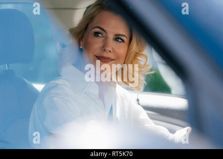Smiling businesswoman in car looking sideways Stock Photo