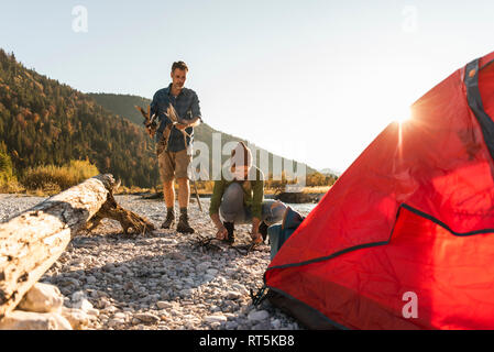 Mature couple camping at riverside, collecting wood for a camp fire Stock Photo