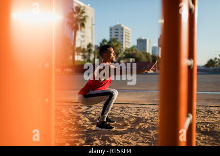 Fit man working out in climbing parcour, doing squats Stock Photo