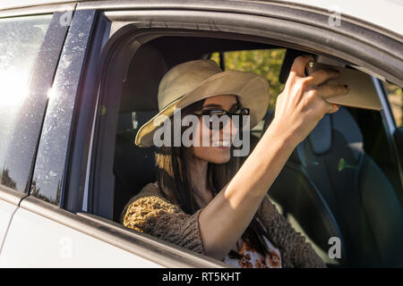 Smiling young woman sitting in a car taking selfie with cell phone Stock Photo