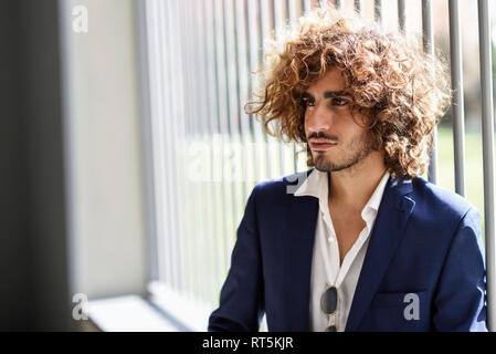 Portrait of young fashionable man with beard and curly hair Stock Photo