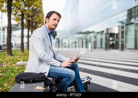 Businessman sitting on a bench, using digital tablet Stock Photo