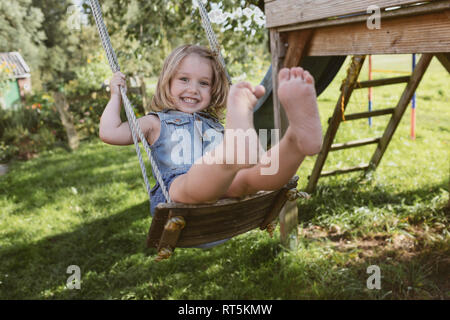 Happy little girl on swing in the garden Stock Photo