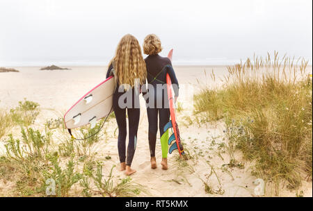 Spain, Aviles, rear view of two young surfers on the beach Stock Photo