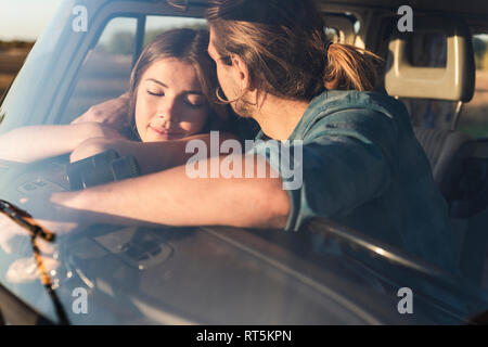 Romantic couple sitting in their camper with arms around Stock Photo