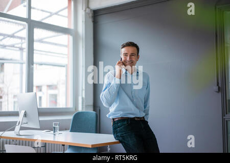 Smiling businessman on cell phone in the office Stock Photo