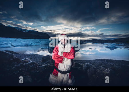 Iceland, portrait of a man disguised as Santa Claus standing at a glacier Stock Photo