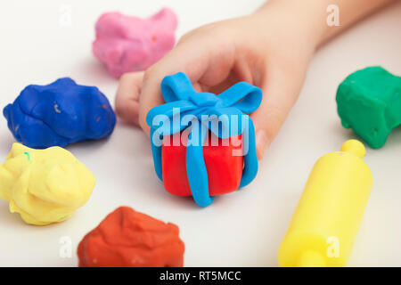 Child playing with playdough and making a giftbox. Close up. Stock Photo