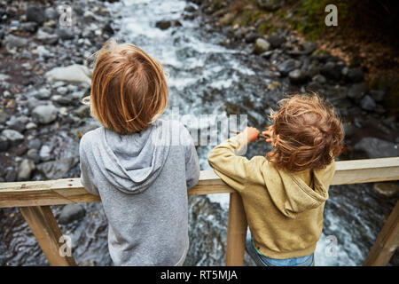 Chile, Patagonia, Osorno Volcano, Las Cascadas waterfall, two boys standing on bridge above a river Stock Photo