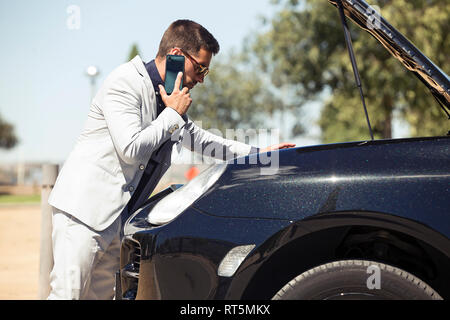 Young businessman having a car breakdown, talking on the phone Stock Photo