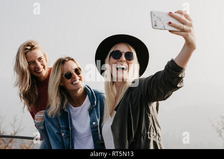 Three happy young women taking a selfie outdoors Stock Photo