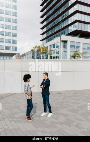 Two colleagues talking outside office building Stock Photo