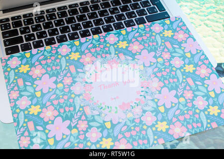 A thank you card sitting on a computer keyboard, online thank you. Stock Photo