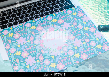 A thank you card sitting on a computer keyboard, online thank you. Stock Photo