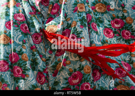 Bird's eye fabric decorated with red and yellow rose flower images and red ribbons waves in the wind. Beautiful designer pattern or background Stock Photo
