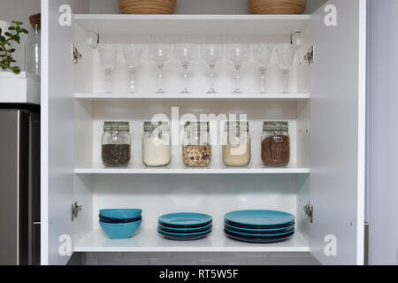 Various seeds in storage jars in pantry, white modern kitchen in background. Smart kitchen organization Stock Photo