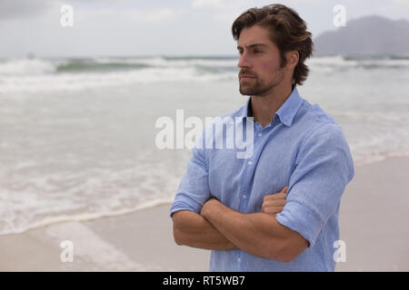 Man standing with arms crossed on the beach Stock Photo
