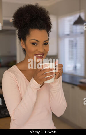 Beautiful woman having coffee in kitchen at home Stock Photo