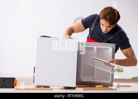 Young handsome contractor repairing fridge Stock Photo