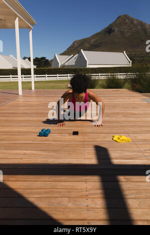 Woman performing push-up exercise in the backyard of home Stock Photo