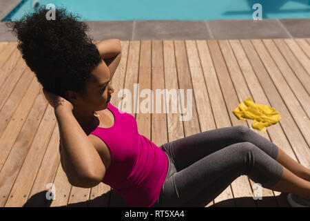 Woman performing crunch exercise in the backyard of home Stock Photo
