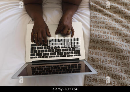 Senior woman typing on laptop in bedroom at home Stock Photo