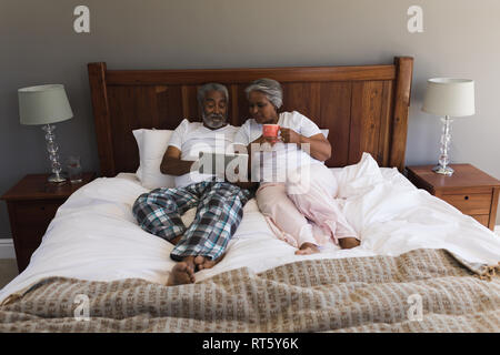 Senior couple using digital tablet in bedroom Stock Photo