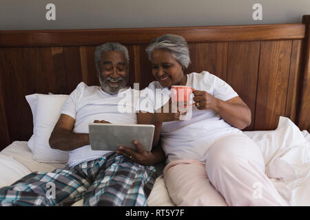Senior couple using digital tablet in bedroom Stock Photo