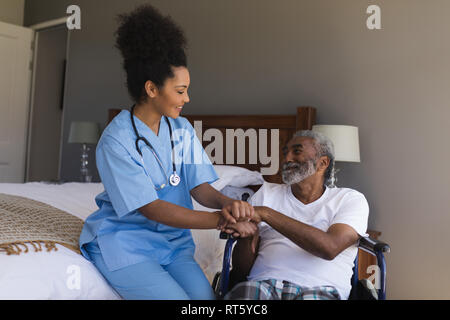 Female doctor consoling senior man in bedroom Stock Photo