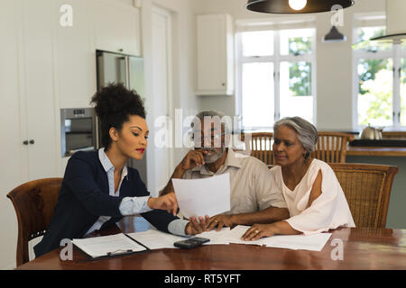 Female real estate agent and senior couple discussing over documents Stock Photo
