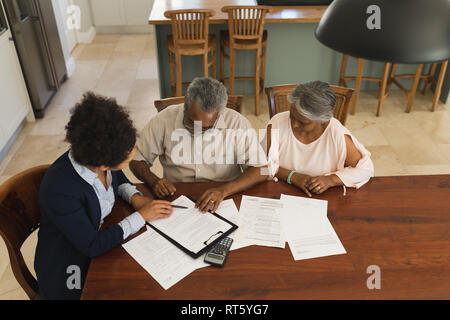Female real estate agent and senior couple discussing over documents Stock Photo